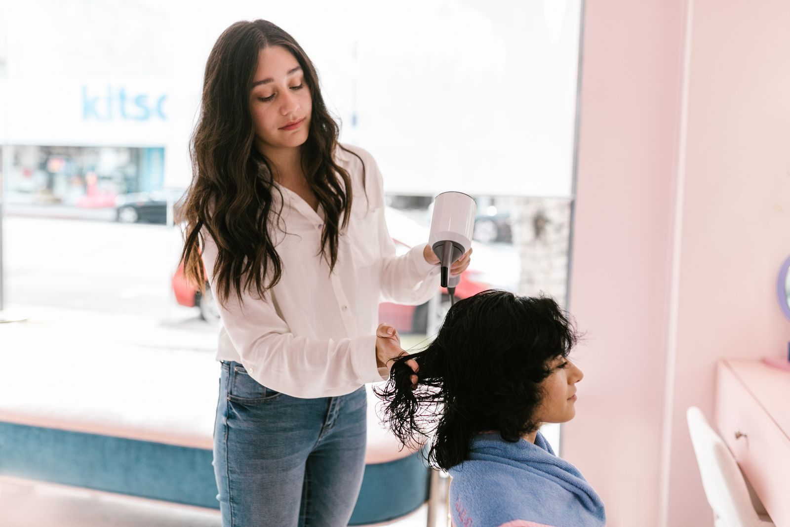 A hairdresser dries a client's hair in a modern salon setting, providing expert hairdressing services