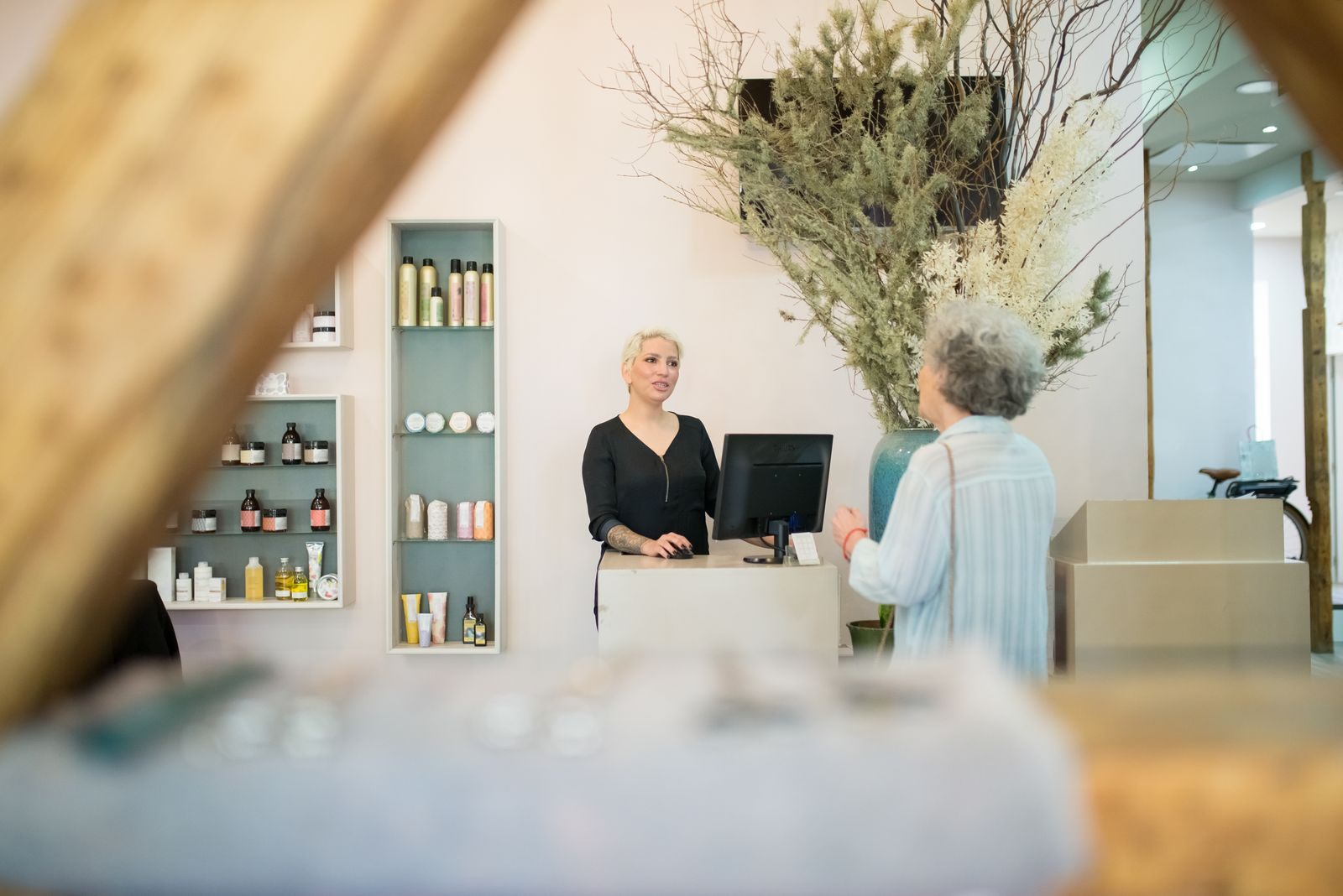 A senior woman conversing with a hairdresser at a stylish salon reception desk