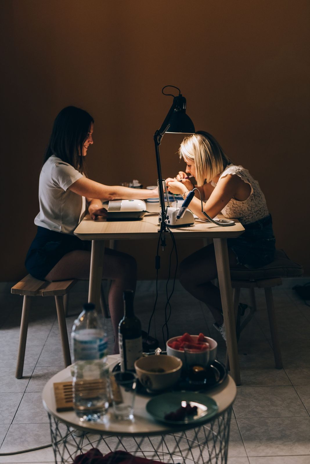 A nail technician providing a manicure to a client in a cozy salon setting. Focus on professionalism and care